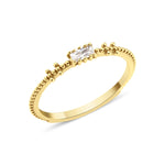 yellow gold beaded band ring with baguette stone on white background