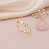 gold beaded band ring with baguette and round stones stepping across the top, on pink satin with dried flowers and a rose quartz stone