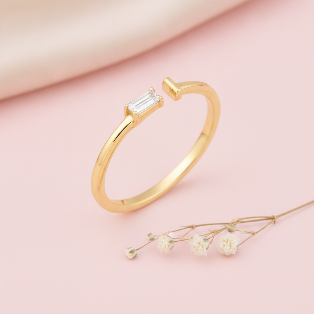 gold open ring with a baguette stone on one end and a smooth tapered tip on the other, on pink satin with dried baby's breath flowers