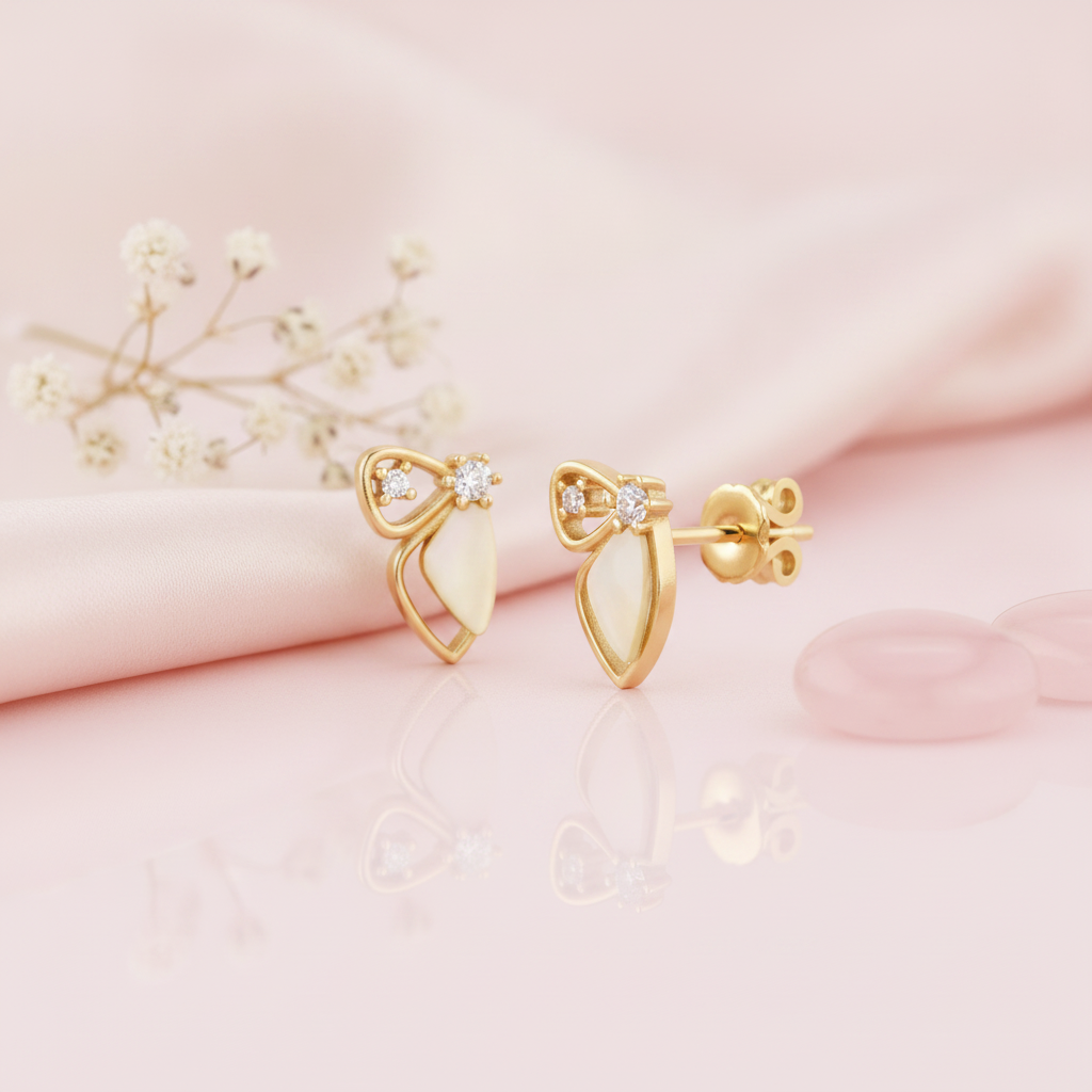 gold bow-and-wing stud earrings with a pale sculpted petal drop and two round accent stones, on pink satin with rose quartz discs