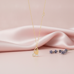 asymmetrical gold butterfly pendant necklace with clear stones on pink satin with lavender sprigs