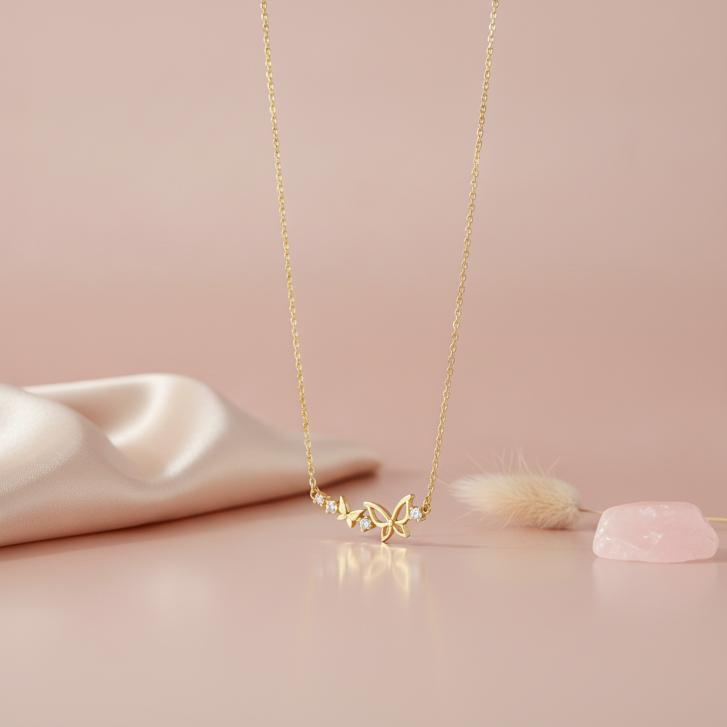 gold butterfly duo necklace with clear stones on pink satin with dried flowers and a smooth stone