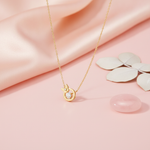 gold circular pendant necklace with butterfly accent and clear stone on pink satin with leaves and rose quartz