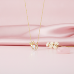 gold bow and halo pendant necklace with clear center stone on pink satin with dried flowers