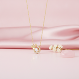 gold bow and halo pendant necklace with clear center stone on pink satin with dried flowers