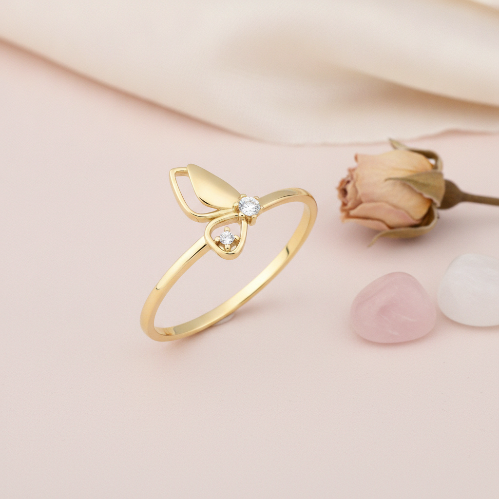 gold butterfly wing ring with two clear stones on pink satin with baby's breath flowers