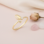 gold butterfly wing ring with two clear stones on pink satin with baby's breath flowers