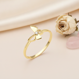 gold butterfly ring with a center clear stone displayed on blush fabric with a dried rose and a rose quartz stone