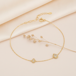 gold chain bracelet with two pave teardrop stations edged in beaded gold, laid in a circle on cream satin with dried flowers