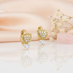 gold huggie hoop earrings with a beaded teardrop and a clear pear-cut stone drop, on peach satin with dried flowers and a rose quartz stone