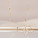 gold station necklace with five graduated pave teardrops on a fine chain, on cream satin with dried flowers