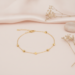 gold chain bracelet with faceted nugget stations displayed on blush pink fabric with dried flowers and a smooth stone