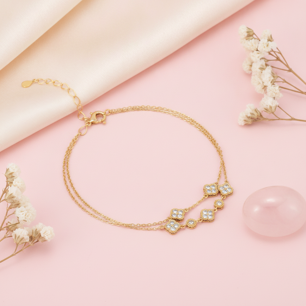 gold double-strand clover bracelet with White CZ stones, styled with dried flowers and a rose quartz stone on a blush background