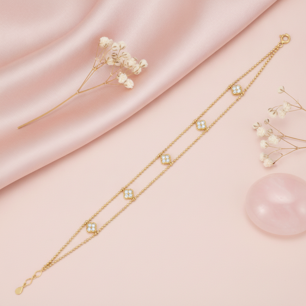 gold beaded double-strand clover bracelet with White CZ stones, styled with dried flowers on a blush background