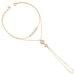 yellow gold hand chain bracelet with bezel-set stones and a floral motif drop on white background