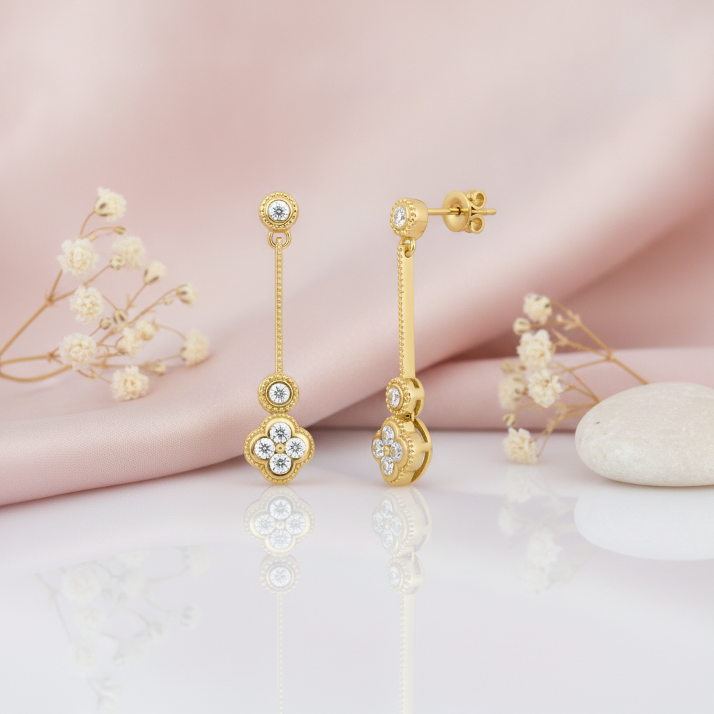 Gold drop earrings with a textured bar and quatrefoil stone cluster, shown front and back on pink satin with dried flowers