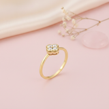 yellow gold four-leaf clover ring styled on a pink background with silk fabric, dried baby's breath, and a rose quartz stone