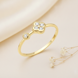 yellow gold clover ring with a single accent stone styled on cream silk fabric with dried baby's breath sprigs