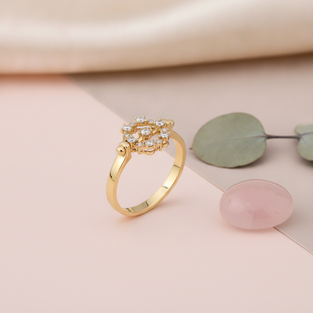 yellow gold ring with a circular cluster of round clear stones, styled on a pink and taupe background with a eucalyptus leaf sprig and a rose quartz stone