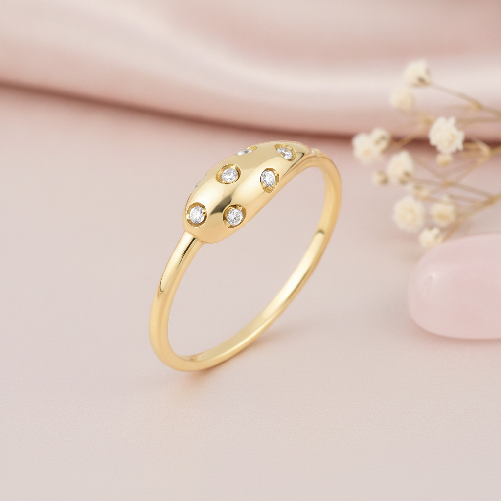 yellow gold domed ring with flush-set stones styled on a pink background with dried baby's breath and a rose quartz stone