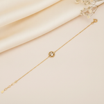 yellow gold beaded circle bracelet with a pearl and clear stones, styled on cream silk with dried baby's breath