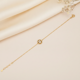 yellow gold beaded circle bracelet with a pearl and clear stones, styled on cream silk with dried baby's breath