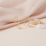 yellow gold hook earrings with a single pearl, styled on cream silk with a dried leaf and a translucent stone