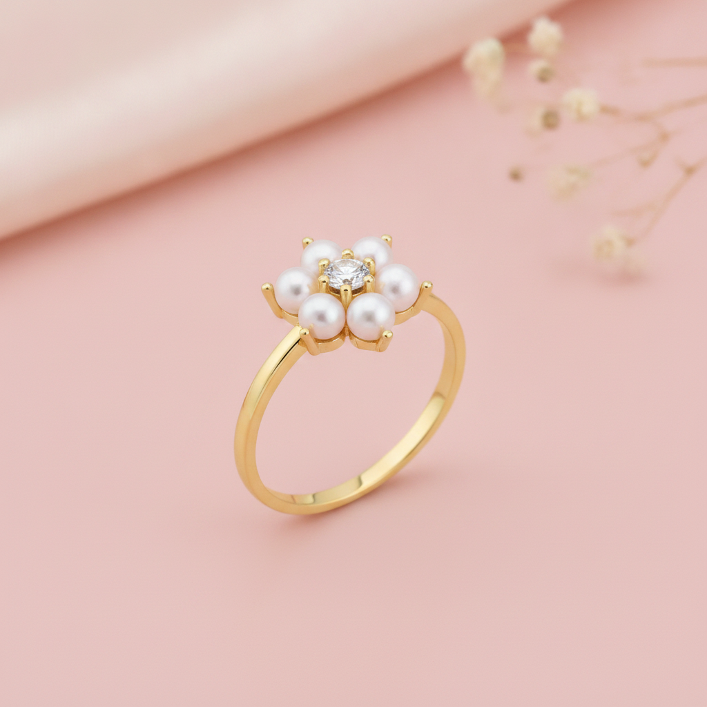 yellow gold floral ring with pearls and a clear stone, styled on a pink background with dried baby's breath