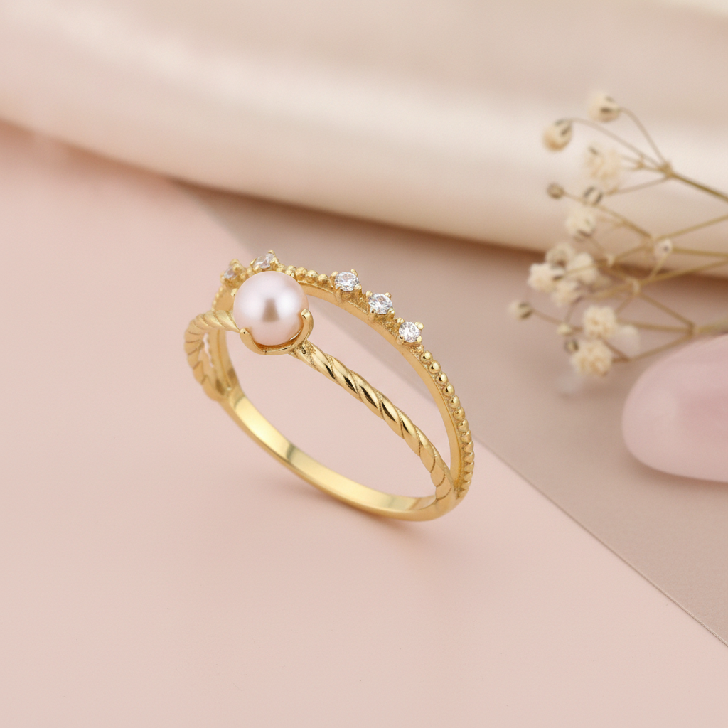 yellow gold solitaire ring with a single pearl, styled on cream silk with a pebble