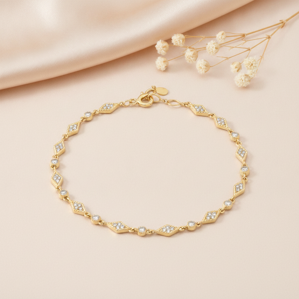 yellow gold chain bracelet with kite-shaped stations and bezel-set stones, styled on cream silk with dried baby's breath