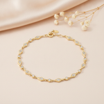 yellow gold chain bracelet with kite-shaped stations and bezel-set stones, styled on cream silk with dried baby's breath