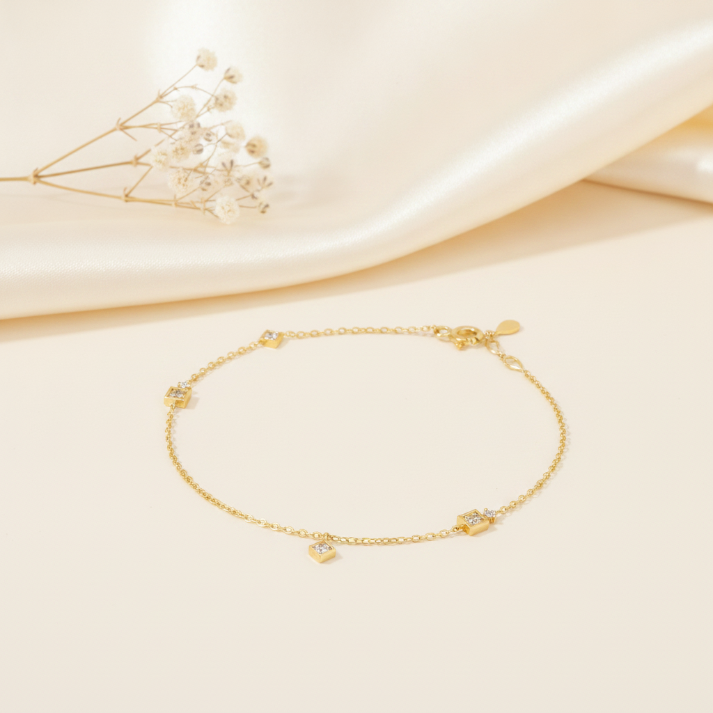 yellow gold chain bracelet with square stone stations, styled on cream silk with dried baby's breath