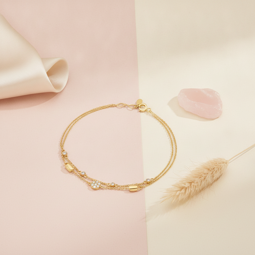 yellow gold double-strand bracelet with a pave stone cluster, styled on a pink and cream background with a dried flower and a rose quartz stone