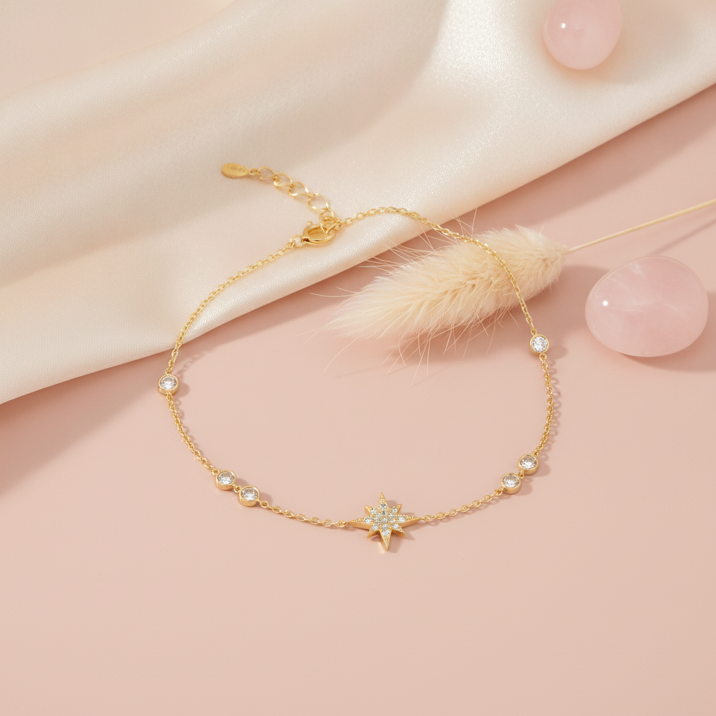 yellow gold star bracelet with bezel-set accent stones, styled on a pink background with a dried pampas plume and rose quartz stones