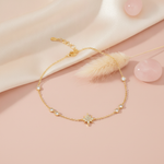 yellow gold star bracelet with bezel-set accent stones, styled on a pink background with a dried pampas plume and rose quartz stones