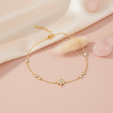 yellow gold star bracelet with bezel-set accent stones, styled on a pink background with a dried pampas plume and rose quartz stones
