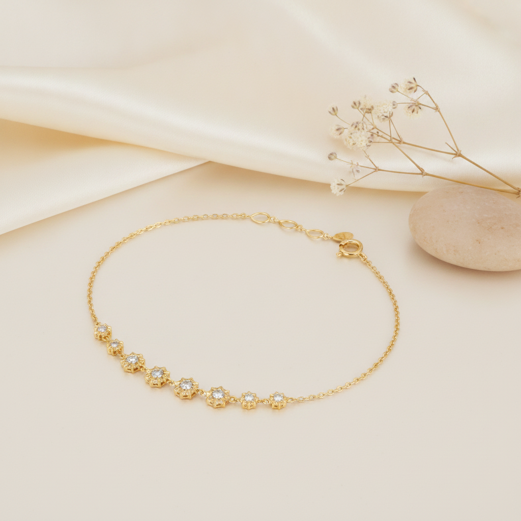 gold bracelet with a row of faceted starburst stone stations, shown on cream fabric with dried baby's breath and a smooth stone