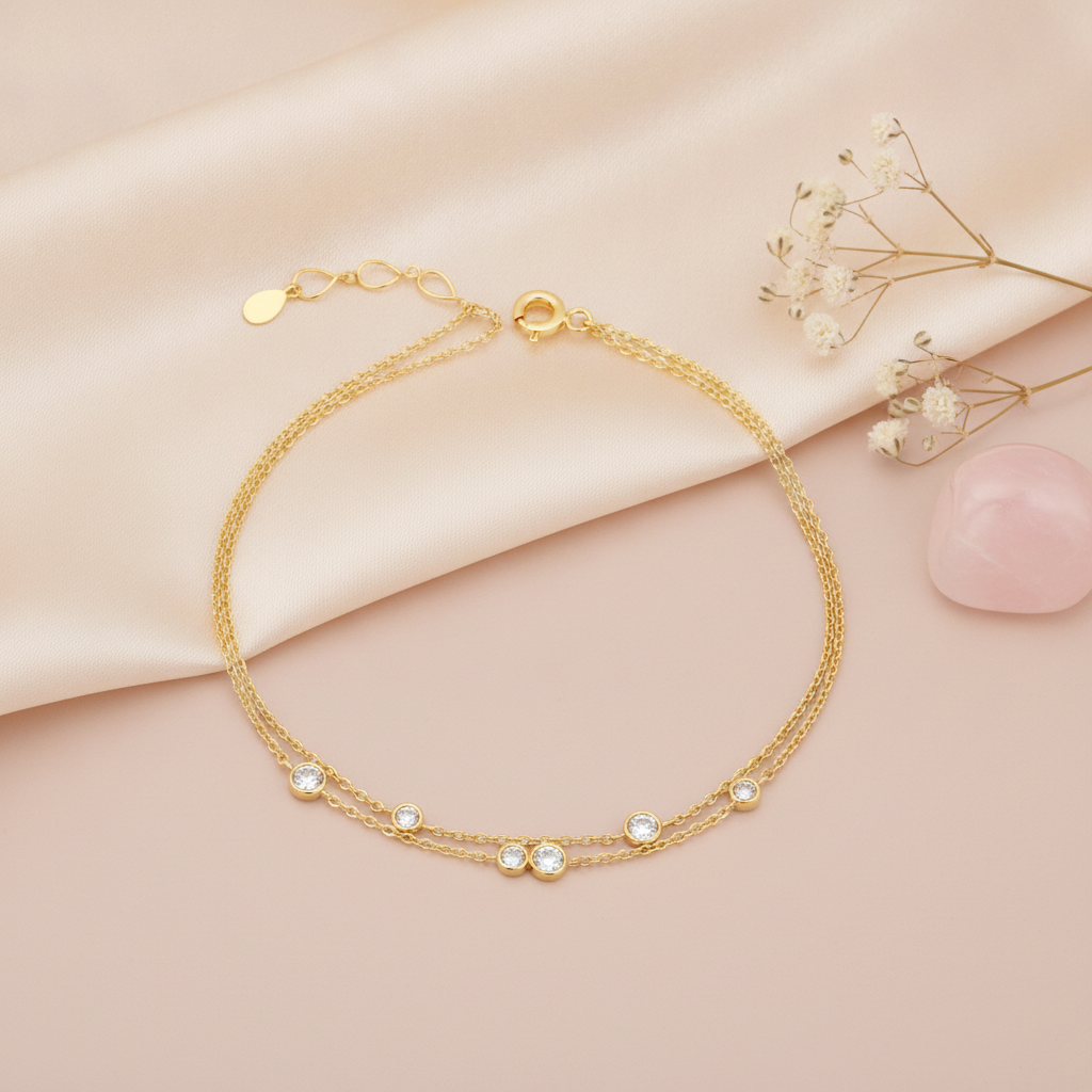 double strand gold bracelet with scattered round bezel-set stones, shown on pink fabric with baby's breath and a rose quartz stone