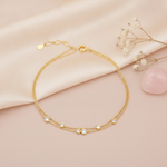 double strand gold bracelet with scattered round bezel-set stones, shown on pink fabric with baby's breath and a rose quartz stone