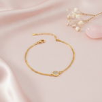 gold bracelet with a pave-set circular disc charm between a single and double chain, shown on pink fabric with baby's breath and a rose quartz stone