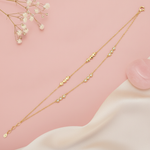 double strand gold bracelet with pyramid stud clusters and small stone accents, shown on pink fabric with baby's breath and a rose quartz stone
