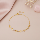 gold bracelet with five openwork heart charms, shown on pink fabric with baby's breath and a rose quartz stone