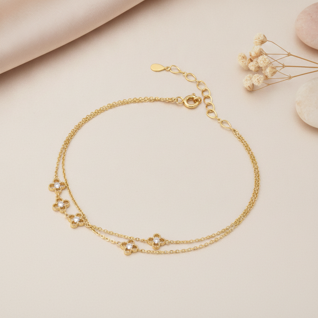 gold bracelet with small clover motif stone stations, shown on cream fabric with dried flowers