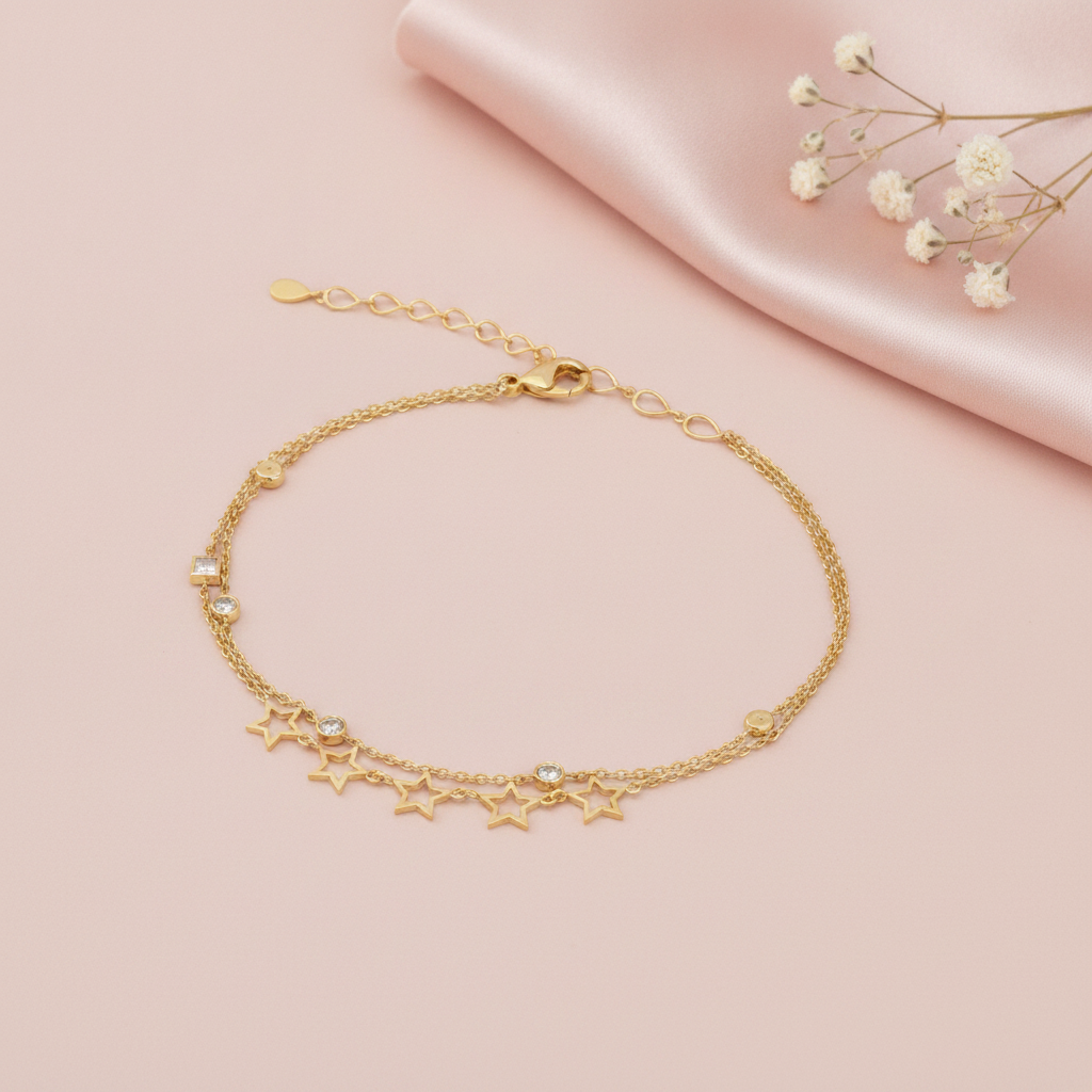 double strand gold bracelet with open star charms and small bezel-set stones, shown on pink fabric with baby's breath