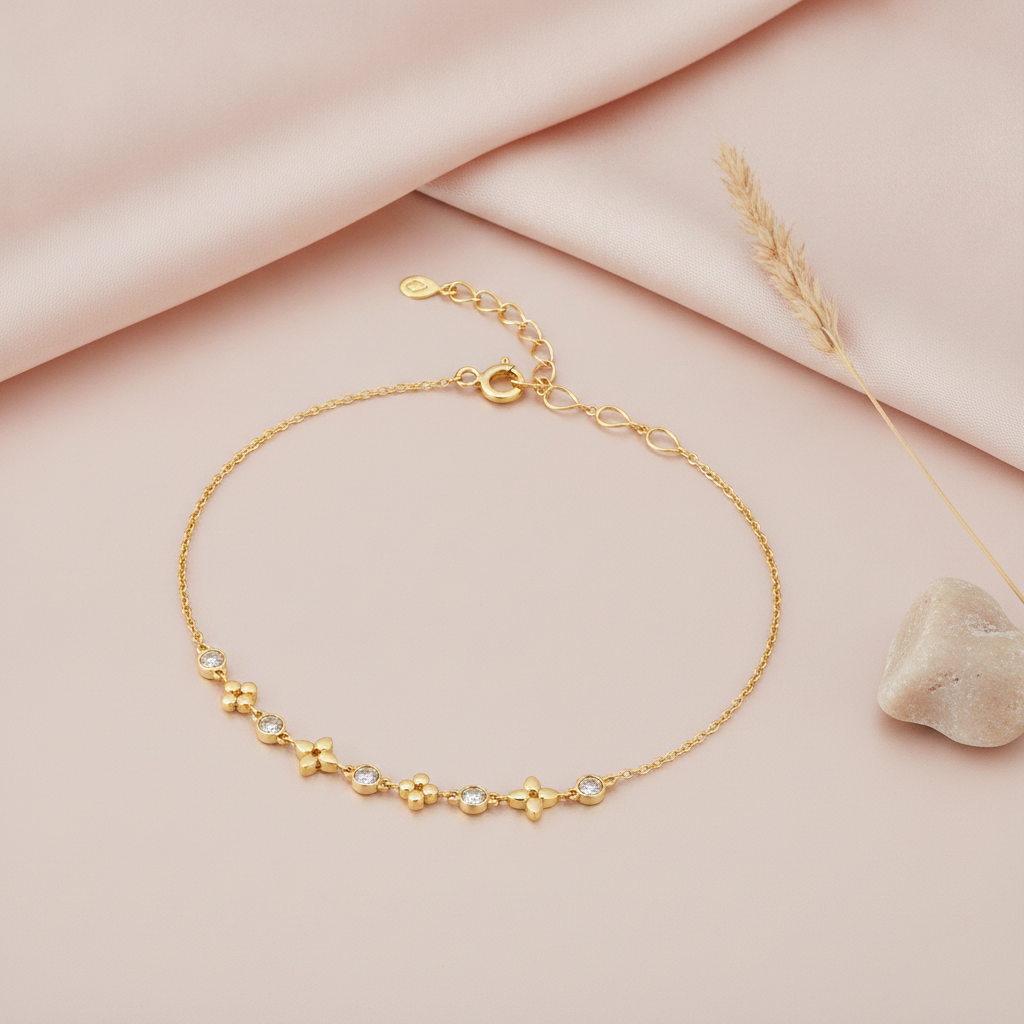 gold bracelet with alternating cushion-shaped stone stations, shown on pink fabric with dried flowers