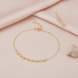 gold bracelet with alternating cushion-shaped stone stations, shown on pink fabric with dried flowers