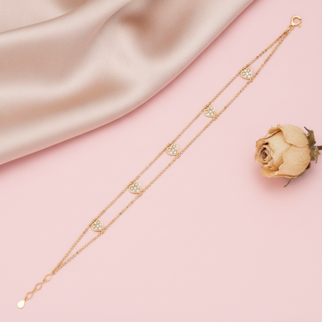 double strand beaded gold bracelet with pave-set heart charms, shown on pink fabric with a dried rose