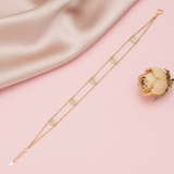 double strand beaded gold bracelet with pave-set heart charms, shown on pink fabric with a dried rose