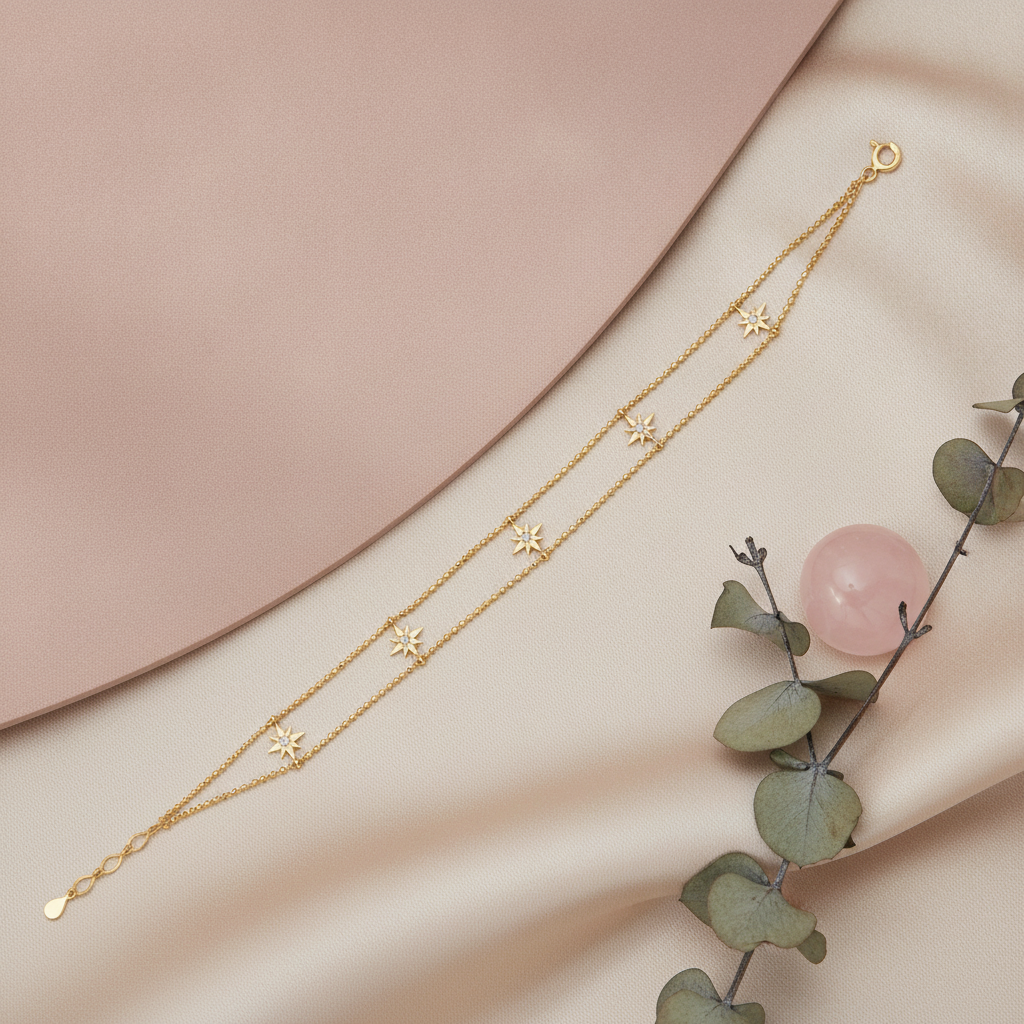 double strand beaded gold bracelet with starburst charms, shown on pink and cream fabric with a rose quartz stone and eucalyptus