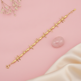 gold bracelet with alternating polished beads, textured stations, and small arrow charms, shown on pink fabric with baby's breath